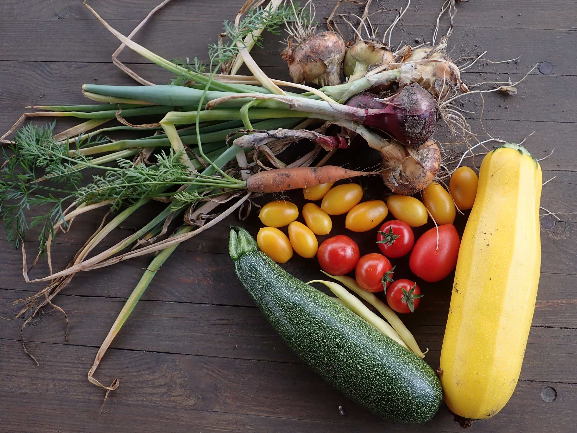 A fresh vegetable harvest laid out on a wooden table